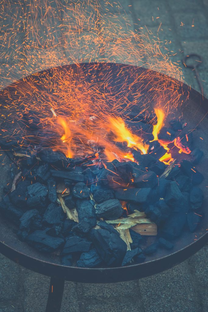 A vibrant scene of flames dancing over charcoal in a fire bowl, creating warmth and ambiance.